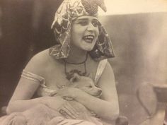 an old photo of a woman with a dog in her lap and wearing a headdress