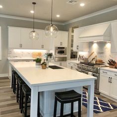 a kitchen island with stools in front of it and lights hanging from the ceiling