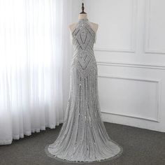 a dress on a mannequin stand in front of a window with white curtains