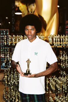 a young man holding an award in front of many awards on display at a store