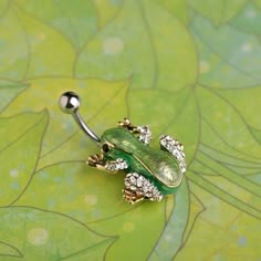 a green frog belly ring with crystal stones on it's back and gold accents