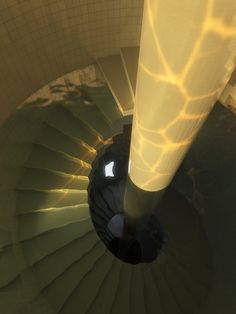 an aerial view of a spiral staircase with sunlight streaming through the top and below it