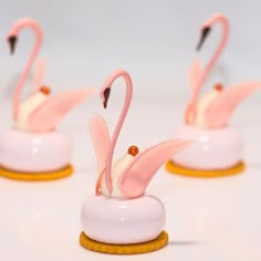 three pink flamingos sitting on top of each other in front of a white background