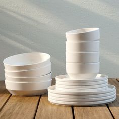 stack of white plates sitting on top of a wooden table