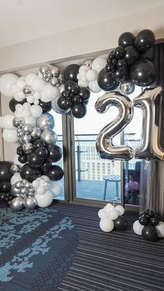 an entrance decorated with black, white and silver balloons that spell out the number twenty