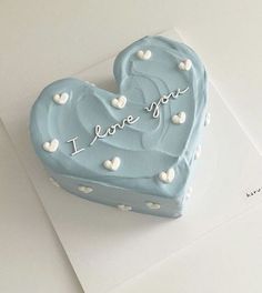 a blue heart shaped cake with i love you written on the top and white hearts around it