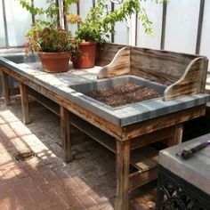 an outdoor table with potted plants on it and a bench made out of pallets