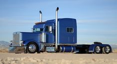 a blue semi truck parked in the desert