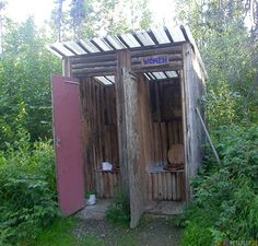 an outhouse in the woods with two doors open