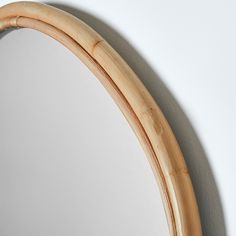 a round mirror hanging on the wall next to a white wall with a wooden frame