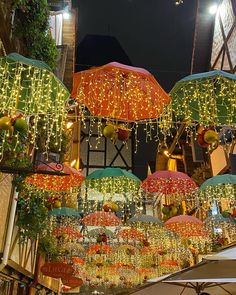 many lights and umbrellas hanging from the ceiling in an outdoor market area at night