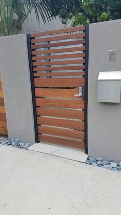 a modern gate with wooden slats on the sides and stone edging around it