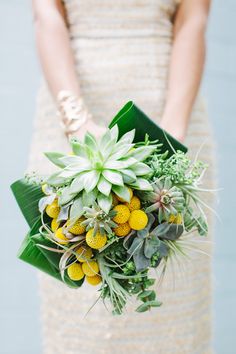 a woman holding a bouquet of flowers and greenery