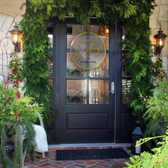 a black front door with christmas greenery around it and the words happy holidays written in gold