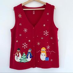 a red sweater with snowmen on it is hanging from a wooden hanger in front of a white wall