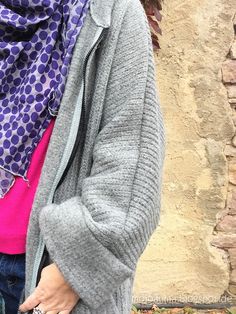 a woman standing in front of a brick wall wearing a purple and blue polka dot scarf