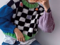 a woman taking a selfie while wearing a sweater and holding a cell phone up to her face