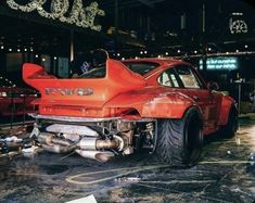 an orange car is parked in a garage with its hood up and exhaust pipes exposed