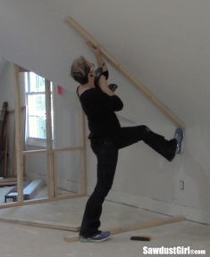 a woman standing on top of a wooden beam in an unfinished room with no walls