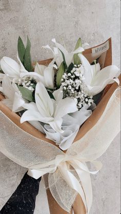 a bouquet of white flowers wrapped in brown paper