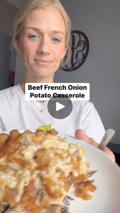 a woman holding a white plate with food on it and the caption beef french onion potato casserole