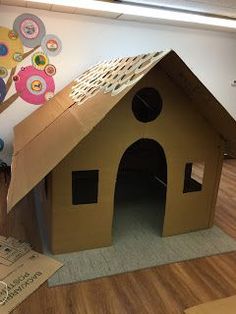 a cardboard dog house made to look like it is in the middle of a room