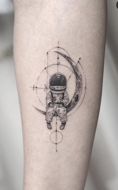 a tattoo on the leg of a person with an astronaut's helmet and moon