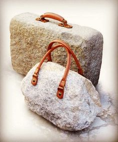 a handbag sitting on top of a rock next to a large rock in the snow