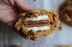 a person holding a cookie with marshmallows and cream on it in their hand