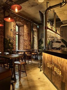 the interior of a restaurant with tables and stools, brick walls and exposed ceilings