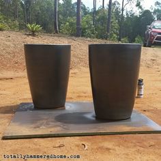 two planters sitting on top of a cement slab in front of a truck and trees