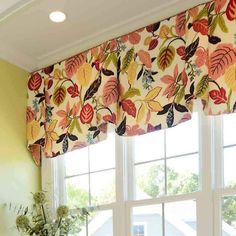 the window is decorated with colorful flowers and leaves on it's valance, along with a potted plant