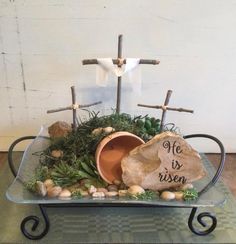 a glass tray with rocks, moss and crosses on it that says he is risen