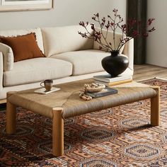 a living room with a couch, coffee table and rug on the floor in front of it