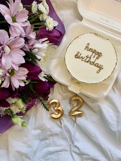 a birthday cake sitting on top of a table next to flowers