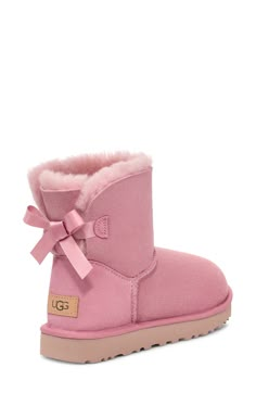 A satin bow adorns the back of a supremely cozy boot made from plush genuine shearling. Pretreated to repel water and stains, the boot also features a Treadlite by UGG™ sole for added cushioning, traction and durability. 1 1/4" heel 1" platform (size 9) 6 1/2" shaft Pull-on style Water-repellent Leather upper/genuine-shearling lining/synthetic sole Shearling may be sourced from Australia, Ireland, the UK, or the USA. See packaging for confirmed country of origin Imported Cute Uggs Boots, Ugg Boots Aesthetic, Pink Bow Uggs, Pink Uggs With Bows, Pink Bailey Bow Uggs, Cute Winter Shoes, Uggs Pink, Uggs Mini, Ugg Mini Bailey Bow