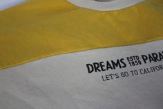 a yellow and white shirt with the words, dreams estd paragon let's go to california