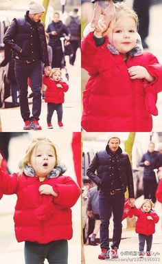 a man and woman walking down the street with two children in red coats on their shoulders