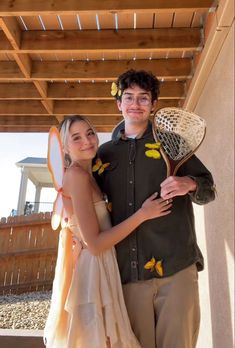 a young man and woman standing next to each other holding tennis racquets