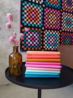 there are many different colored papers next to a vase with pink flowers on the table