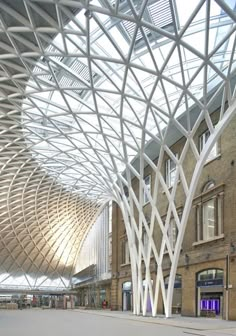 the interior of an indoor shopping mall with large white columns and glass roof over it