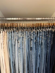 several pairs of jeans are hanging in a closet