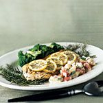 a white plate topped with chicken and lemon slices next to broccoli on a table