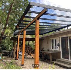 a patio covered in wood and surrounded by trees, with a grilling area next to it