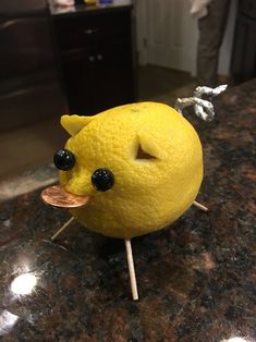 a lemon with eyes and nose sticking out of it's mouth on top of a table