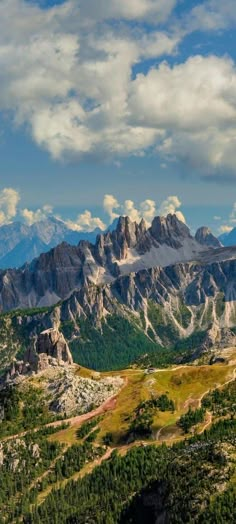 the mountains are covered in snow and green grass, under a blue sky with white clouds