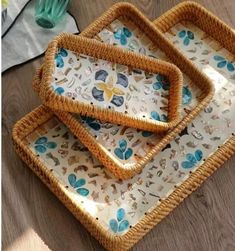 three wicker trays with blue flowers on them sitting on top of a wooden table