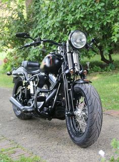 a black motorcycle parked on the side of a road next to some grass and trees