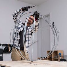 a man is holding a circular object in his hands while standing on top of a table