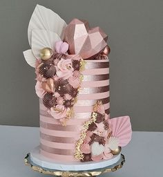 a three tiered cake with pink and gold decorations